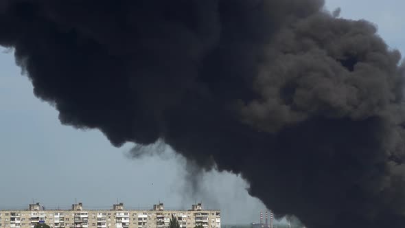 Black Smoke Rises Above the Buildings. A Big Chemical Fire at a Factory Building. Thick Black Smoke alt