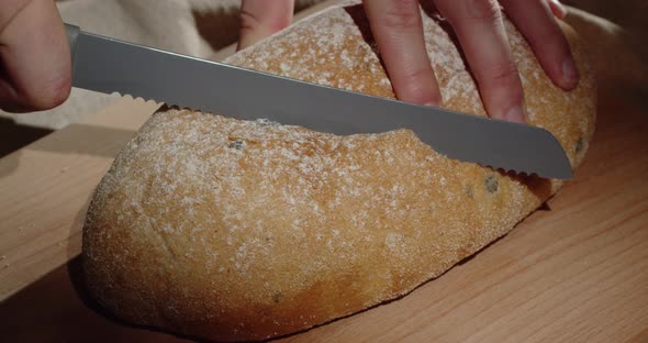 Use A Sharp Knife To Cut A Piece Of Freshly Baked Homemade Bread On A Wooden Board.