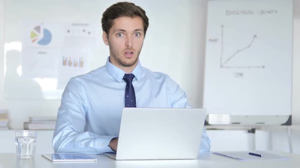 Surprised Young Businessman in Office Looking at Camera Shocked alt