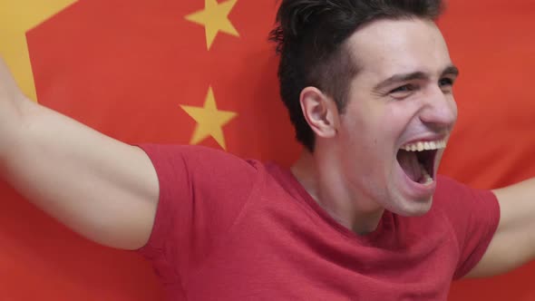 Chinese Young Man Celebrating while Holding the Chinese Flag alt