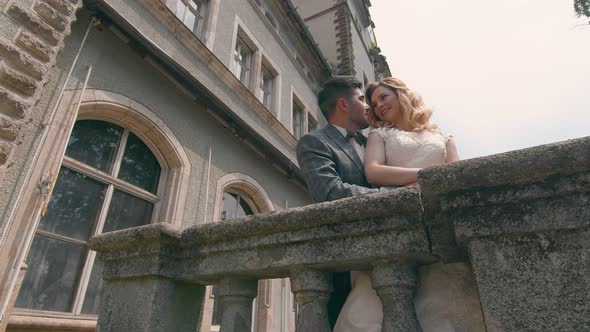 A Young Couple in Love with Two People Standing By a Stone Fence and Hugging. Fast Motion Camera alt