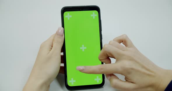 Woman's Hand Holding a Mobile Telephone with a Vertical Green Screen in Tram Chroma Key Smartphone alt