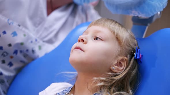 Little child smiles in stomatology chair. Kid patient is given a toy. Healthy teeth concept  alt