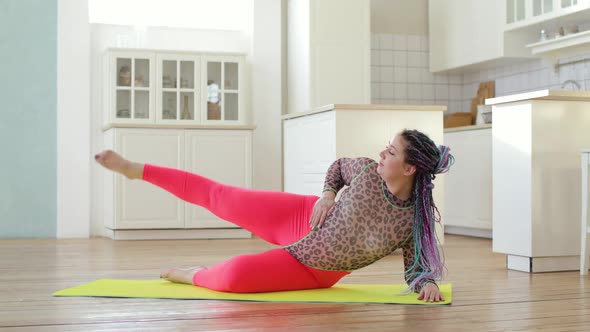Fat Woman in Sportswear Doing Legs Lifting Exercises Lying on Mat at Home