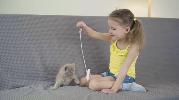 Little Girl Child Playing With Kitten At Home In Room alt