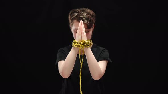 Clasped Female Hands Tied with Rope with Blurred Sad Woman at Background alt