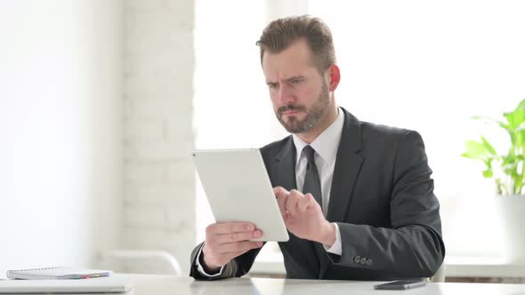 Young Businessman Reacting to Loss on Tablet in Office alt