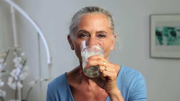 Mature woman drinking a glass of milk alt