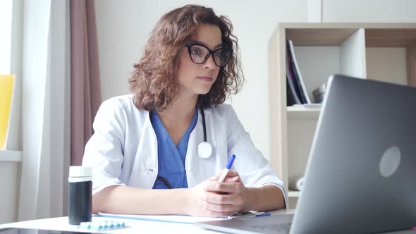 Smiling Female Medical Assistant Video Calling Distant Patient on Laptop alt