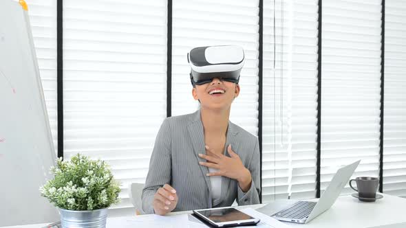 Asian woman use virtual reality glasses ( VR ) in her office