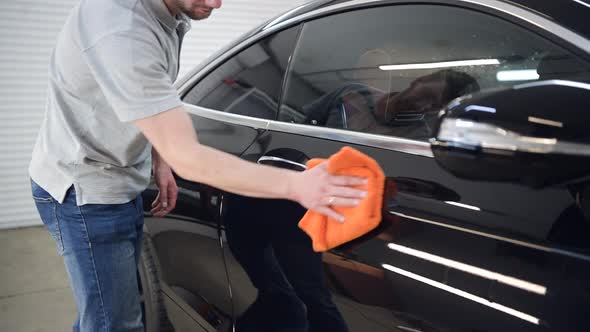 Man Polishes the Car Uses a Microfiber Cloth and Polish To Wipe the Car's Body alt
