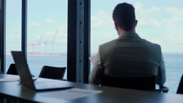 Office Manager Checking Documents at Panorama Window Rear View alt