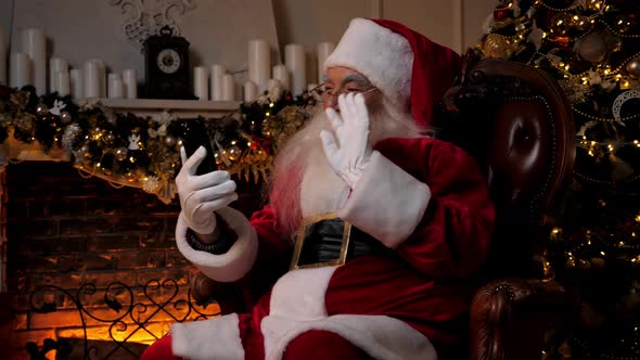 Modern Smiling Santa Claus Greets Talks to Children Online Smartphone Video Call alt