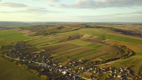 Aerial view of countryside village with small houses among green trees alt