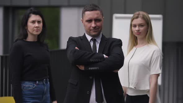 Handsome Confident Caucasian Man and Beautiful Elegant Women Crossing Hands Looking at Camera alt