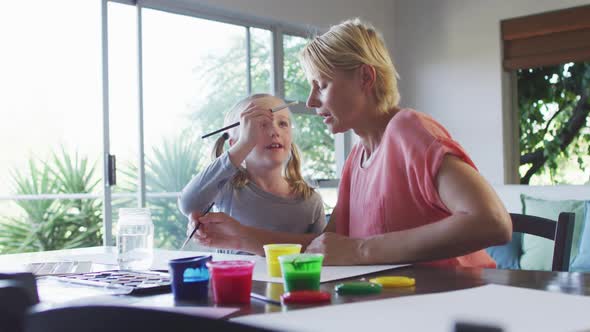 Side view of Caucasian woman painting with her daughter at home alt