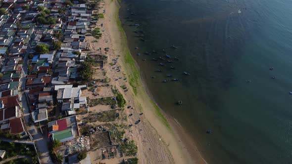Aerial top down of fisherman town with sandy beach and floating traditional basket boats in ocean - alt