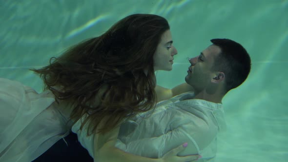 Romantic Wedding Pair is Kissing Underwater in Pool with Blue Background