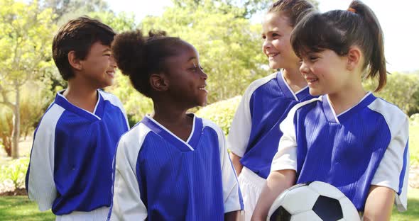 Group of smiling kids standing with football alt