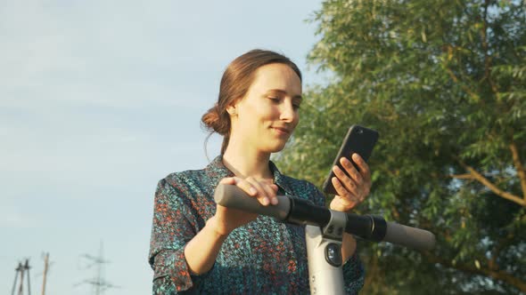 Electric scooter, ecological transport. Girl is standing near electric kick scooter alt