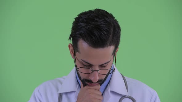 Face of Stressed Young Bearded Persian Man Doctor Thinking and Looking Down alt