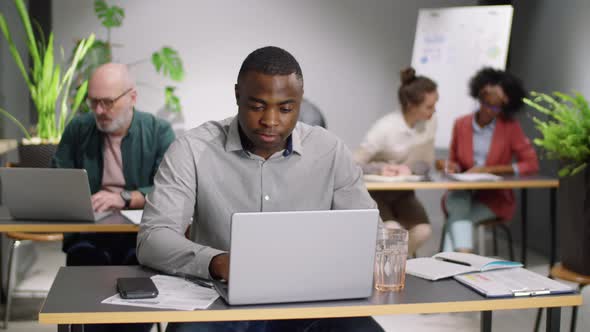 Joyous Afro-American Man Looking at Camera and Smiling at Office Desk alt