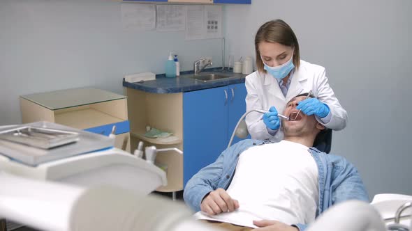 Female Dentist Treating Client's Teeth at Clinic alt