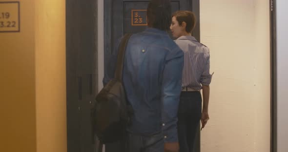 Young Interracial Couple Entering Room in Hostel or Hotel and Closing Door. Charming Caucasian Woman alt