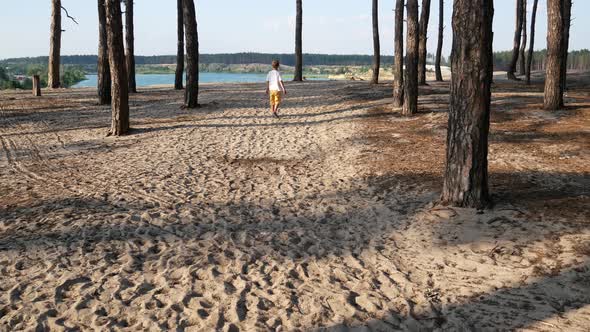 A 56 Year Old Boy Walks Along a Sandy Path in a Pine Forest