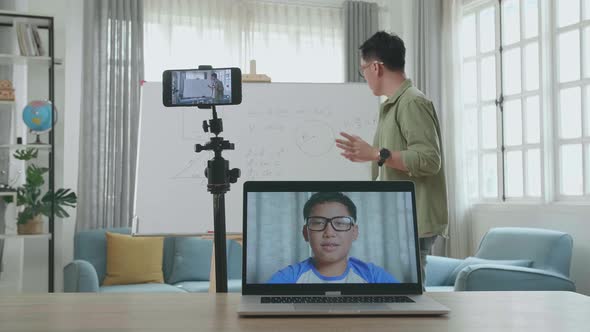 Asian Male Teacher Having Video Call On Laptop While Teaching Math Online With Boy Student At Home alt