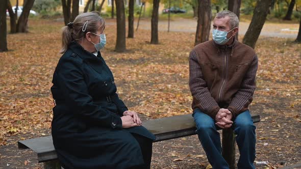 Senior Grandparents Couple in Medical Masks Sitting in Park