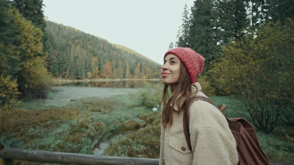 Attractive Hipster Woman in Casual Wear and Hat with Backpack Hiking in Forest in Autumn alt