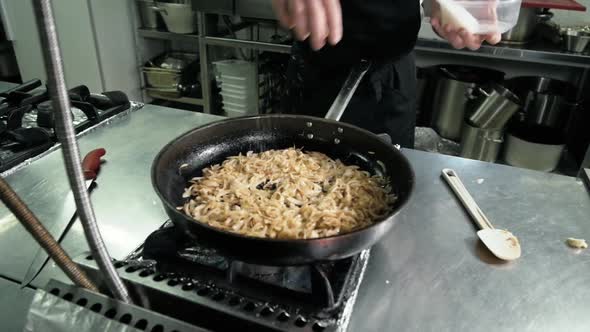 Chef is Making Flambe Sauce on Restaurant Kitchen with Onion and Wine alt