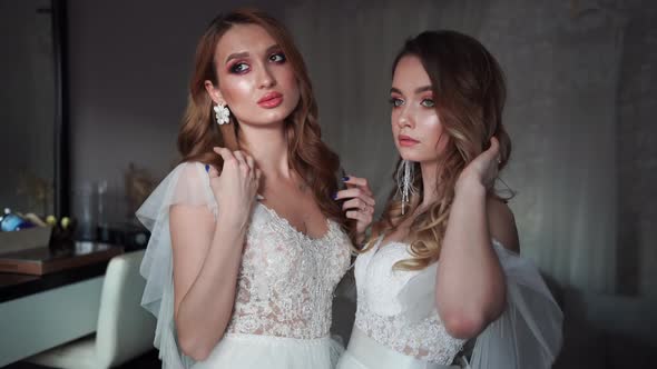 Two Young Models Posing in Front of the Photographer in a Wedding Dress. alt