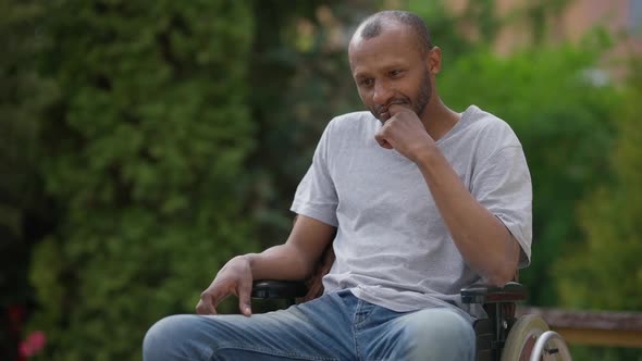 Medium Shot Portrait of Thoughtful African American Man Sitting in Wheelchair Outdoors alt