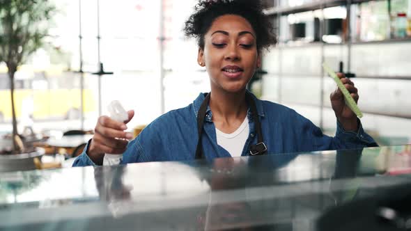 A african american cafe worker woman cleaning the bar counter alt