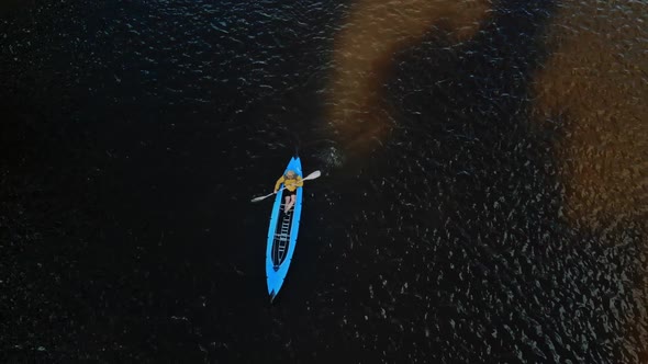 A Young Strong Man Swims in a Blue Kayak