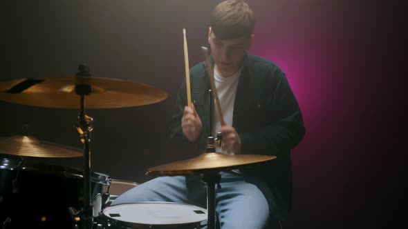Drummer Playing the Drum Set in a Dark Room on a Black Background alt