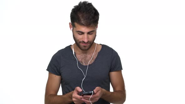 Caucasian Thin Male Model Posing Over White Background Listening Music Using Cellphone and alt
