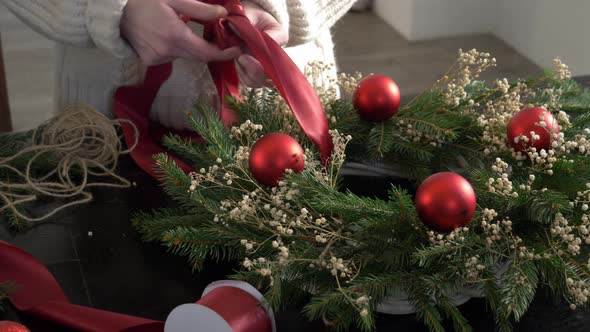 Female decorates the Christmas wreath herself on table at home