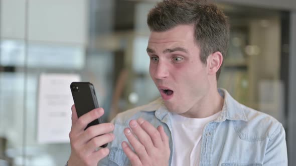 Portrait of Sad Young Designer Getting Loss on Smartphone alt