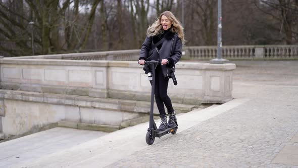 Excited Woman Riding Electric Scooter Near Steps alt