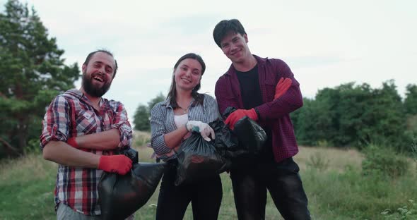 Portrait of Cheerful Young Team of Volunteers with Garbage Bags Smile at Camera alt