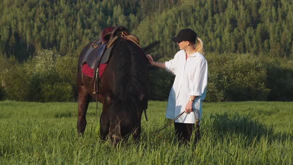 A Young Blonde Girl Strokes the Horse's Mane alt