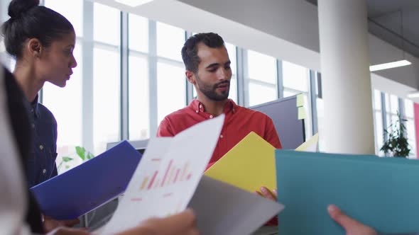 Diverse group of business colleagues holding documents discussing alt