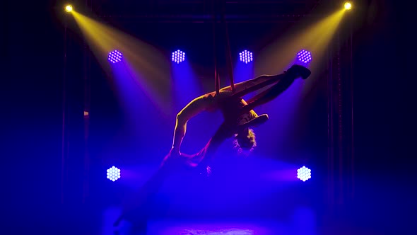 Female Aerial Gymnast Performing Rotate and Twine on a Red Silk. Exciting Acrobatic Show, Dark Smoky alt