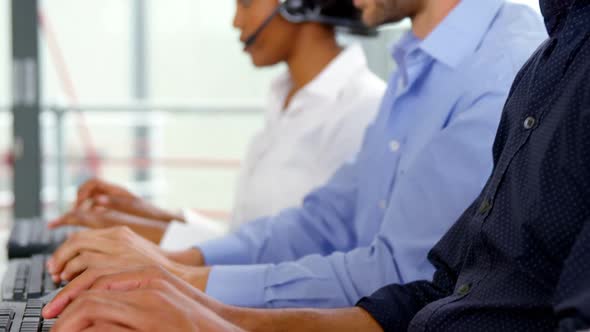 Business executives with headsets using computer alt