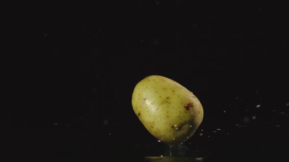 Potato Falls In Water In Dark And Splashes Scatter In Different Directions
