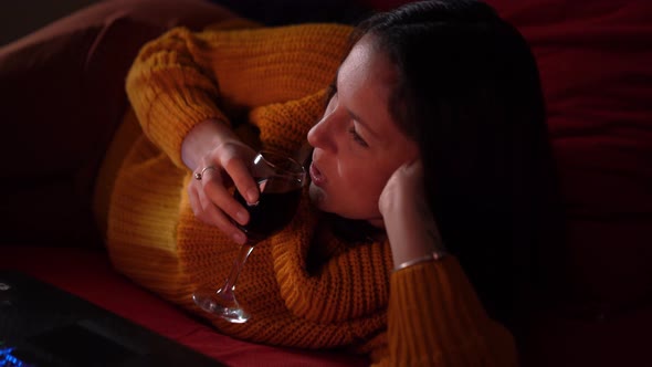 Happy Woman Watching a Movie on Laptop with Wine
