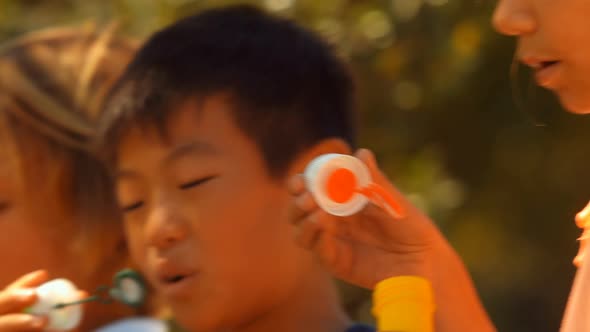 Close-up of schoolkids playing with bubble wand alt